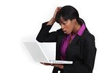 An African American businesswoman looking at her laptop with a dubious expression.