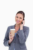 Smiling tradeswoman with paper cup on her cellphone