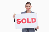 Smiling real estate agent presenting sold sign