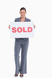 Happy real estate agent holding sold sign