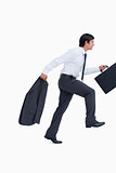 Side view of sprinting businessman with suitcase and jacket