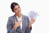 Smiling female entrepreneur pointing at money in her hand
