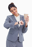 Smiling female entrepreneur with paper cup looking at her watch