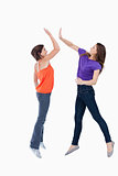 Two teenagers jumping while trying to join their hands