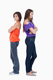 Two girls standing back to back with their arms crossed