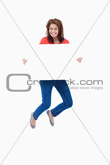 Excited teenager jumping while holding a blank poster