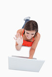 Attractive young woman saying hello to her computer while lying 