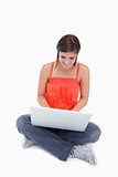 Attractive teenage girl sitting cross-legged typing on a laptop