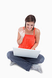 Smiling teenage girl saying hello to her laptop while sitting cr