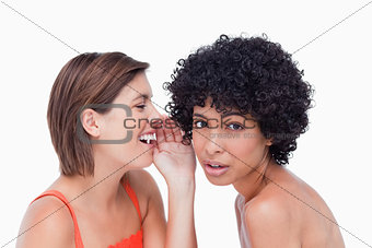 Teenage girl being told a secret by a friend