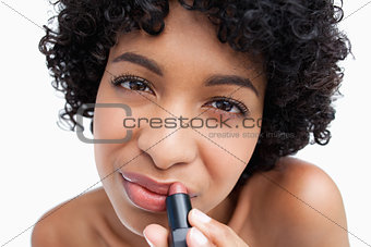 Young brunette applying lipstick against a white background