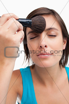 Young calm woman closing her eyes while applying make-up