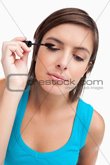 Young woman almost closing her eyes while applying mascara