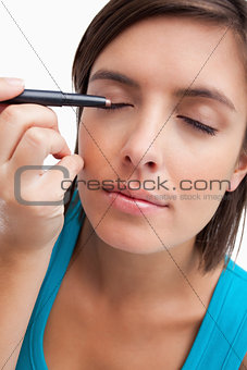 Young woman using an eye pencil to apply make-up