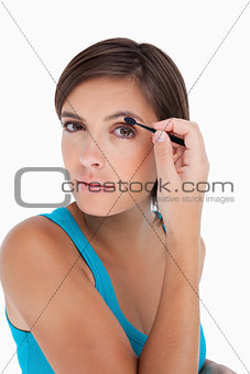 Beautiful teenager putting eyeshadow on her eyelid