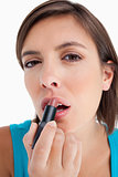 Attractive teenager applying lipstick against a white background