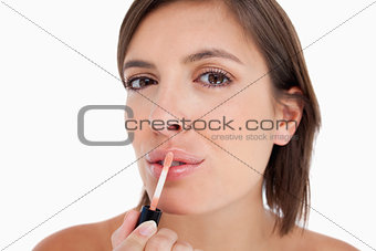 Young woman applying lip gloss with the brush included