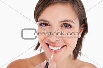 Teenager smiling while applying lip gloss with a lip brush
