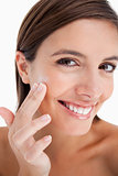Attractive teenage girl putting moisturizer cream on her face