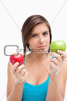 Serious teenage girl holding a green and a red apple