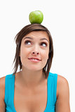 Attractive young woman standing upright with a green apple on he