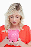 Young woman looking at a piggy bank held by her hands