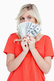 Attractive woman hiding her face behind dollar bank notes