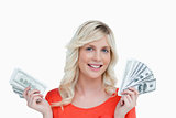 Smiling woman holding two fans of dollar notes in her hands