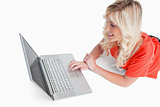 Smiling woman lying down while looking at her laptop