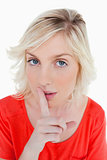 Young blonde woman telling to be quiet with her finger on her mo