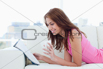 Young woman reading a magazine on a sofa with a cup of coffee
