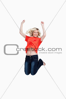 Dynamic teenager energetically jumping while raising her arms ab
