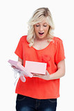Young blonde woman showing her surprise while opening a present