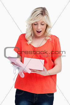 Young blonde woman showing her surprise while opening a present