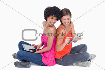 Smiling teenage proudly showing her tablet PC to her friend