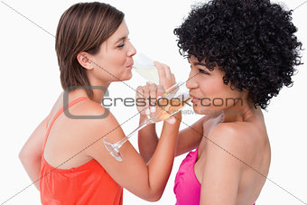 Young women crossing their hands together while drinking champag