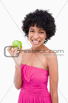 Young woman beaming while holding a beautiful green apple