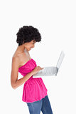 Attractive teenager standing upright while holding a laptop