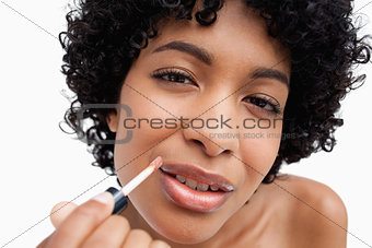 Beautiful teenage girl applying lipstick against a white backgro