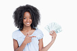 Young smiling woman pointing her finger on a fan of dollar notes