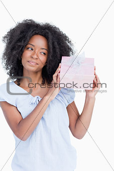 Young woman shaking her gift in order to guess what it is
