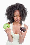 Young woman hesitating between a chocolate muffin and a green ap
