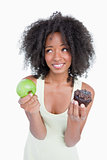 Young woman looking up to ask for help to choose between a fruit