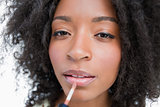 Young woman using a lip gloss applicator to make-up