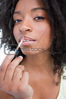 Young woman applying gloss in a concentrated way