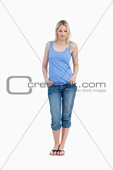 Relaxed blonde woman standing upright with hands in pockets