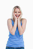 Happy blonde woman showing her surprise by placing her hands on 