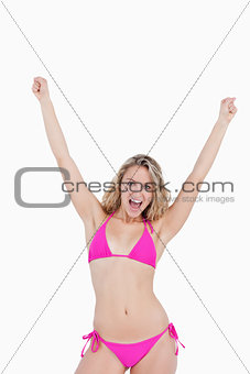 Young attractive woman in beachwear raising her arms above the h