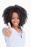 Young smiling woman standing upright while placing her thumbs up
