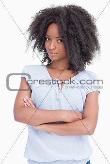 Serious young woman with curly hairstyle crossing her arms